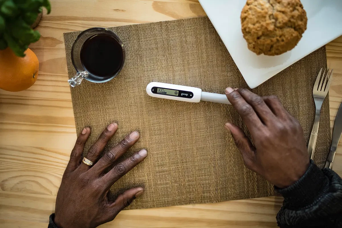 Gocap on an insulin pen beside a breakfast plate, at home on the table